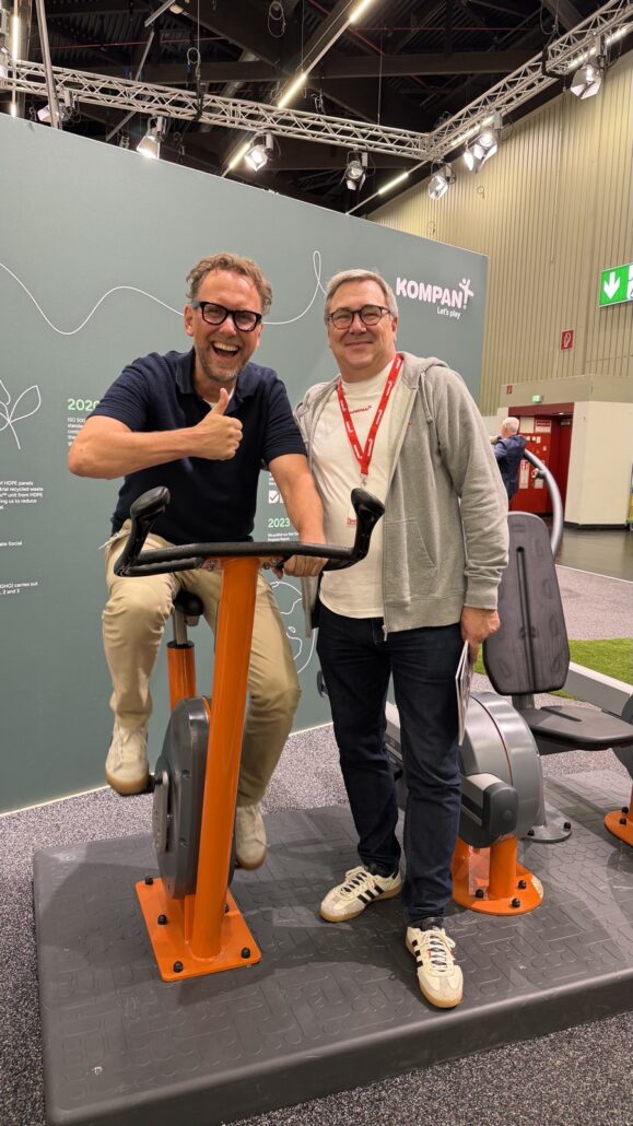 Michael Leibrecht auf einem Outdoor-Ergometer von KOMPAN neben International Key Account Manager Sten Frydensbjerg